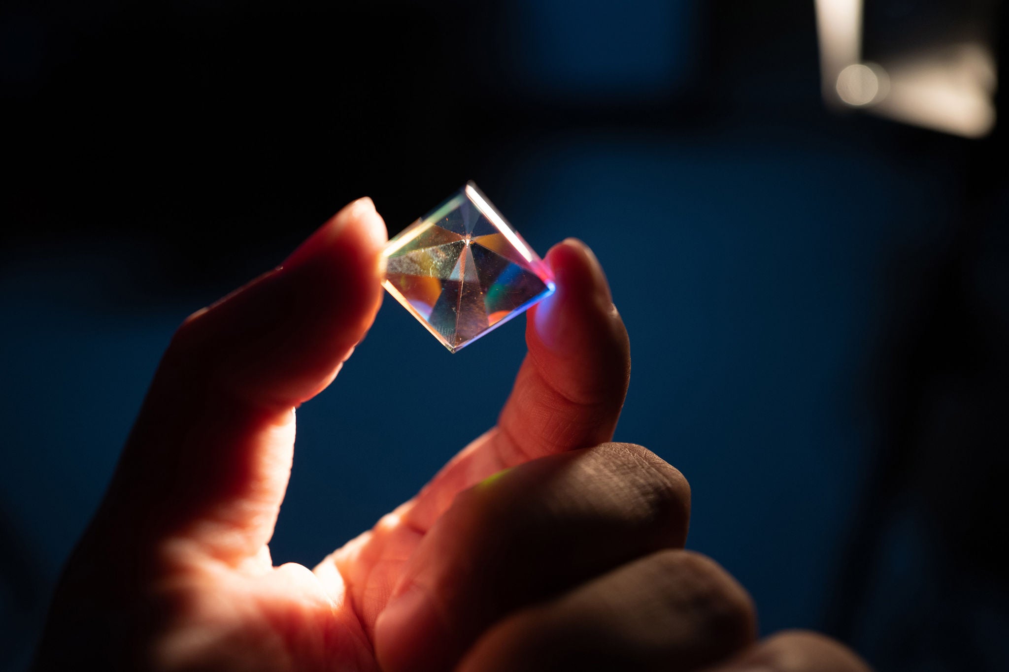 Rhombus crystal being held between persons fingers